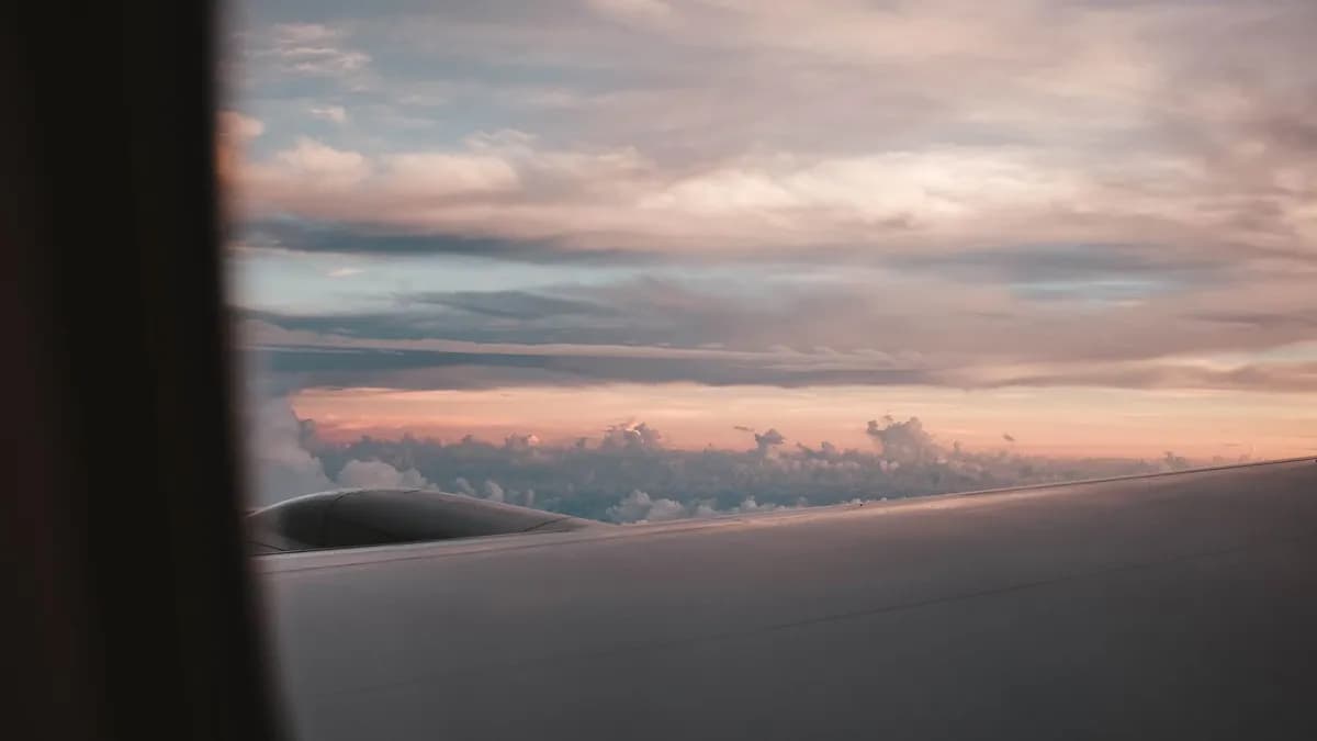 Airplane wing above clouds at sunset