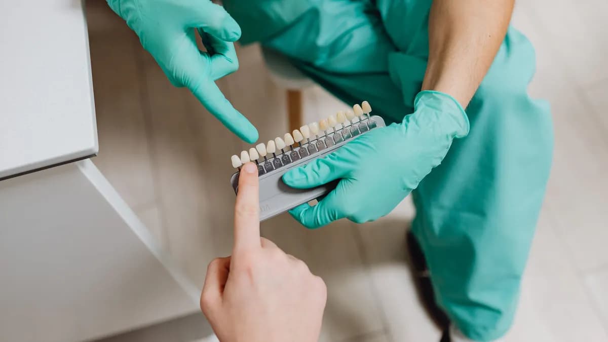Dentista comparando una guía de tonos dentales durante la consulta